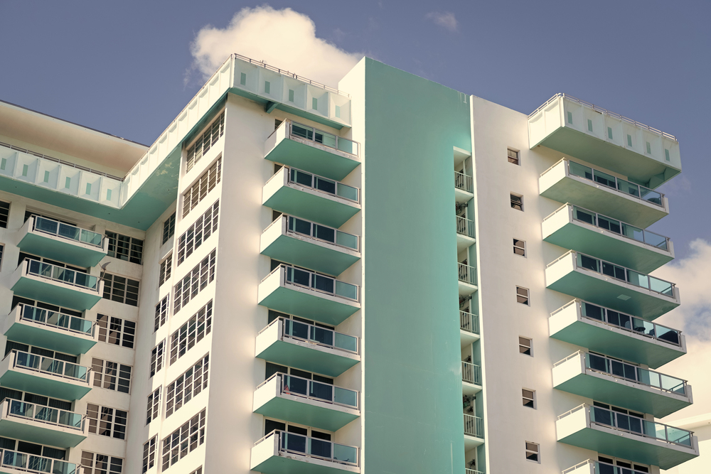 Modern mid-rise building with balconies and blue accents.
